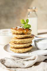 Breakfast with oatmeal pancakes with jam, yogurt and non-dairy milk, light concrete background. Healthy vegetarian food concept.