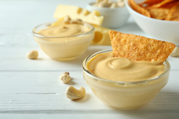 Snacks with cheese sauce on white wooden table
