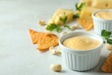 Cheese sauce and snacks on white textured table
