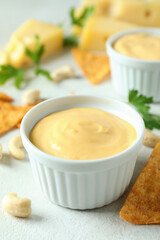 Cheese sauce and snacks on white textured table