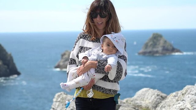 A young mom on vacation at Pen Hir Point on the Crozon Peninsula in French Brittany, the famous three islets, France. Vertical photo