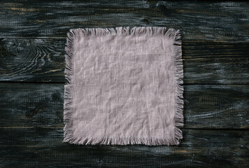 Pink linen napkin with fringe on a wooden background, rustic style, top view, space, toned