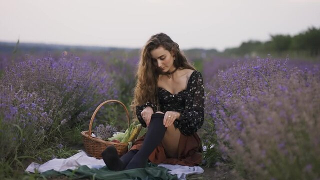 Sensual woman on lavender field, putting on black tights, slow motion