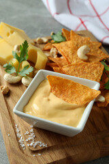 Board with cheese sauce and snacks, close up