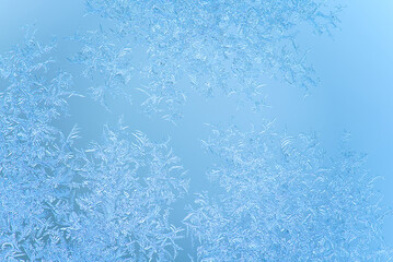macro shot of natural frost patterns on window in winter day on blue background. arctic wallpaper. crispy frost structure ornament