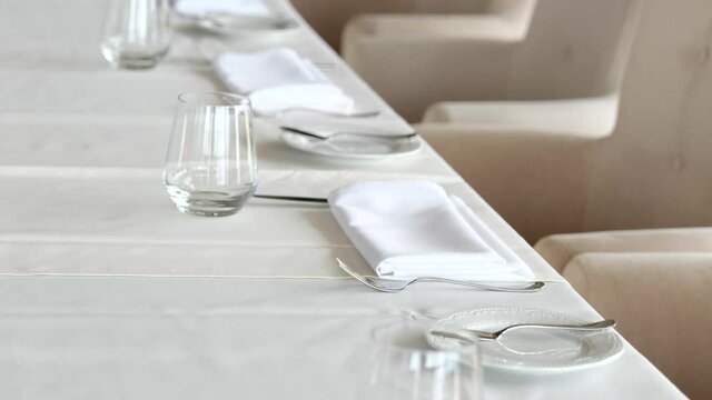table festive served with glasses, plates, napkin in modern restaurant. Weeding, banquet or festive dinner celebration with white tablecloth. Elegant cutlery is arranged according etiquette
