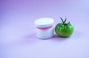 Cream and mask for skin care in white jar and tube with  dispenser near bright juicy tomatoes. Concept Useful Natural Cosmetics from Tomato with Vitamins and Antioxidants.