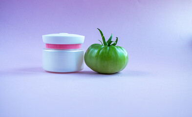 Cream and mask for skin care in white jar and tube with  dispenser near bright juicy tomatoes. Concept Useful Natural Cosmetics from Tomato with Vitamins and Antioxidants.