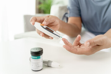 Mature Asian woman checking blood sugar level by Digital Glucose meter, Healthcare and Medical, diabetes, glycemia concept