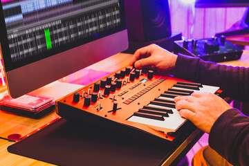 professional sound designer hands playing and tweaking analog synthesizer keyboard knobs for...