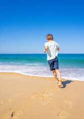 Happy boy running and playing on the summer beach. Young teenager relax and having fun in summer holiday vacation travel. High quality photo