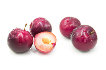 Ripe fresh organic plums whole and half in water drops isolated on white background.	