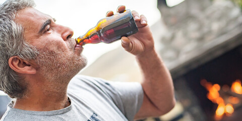 Adult man drinking beer at the barbecue party in the backyard of the weekend cottage. BBQ grilling party