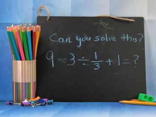 A board with a mathematical equation to solve with school supplies. Back to school concept.