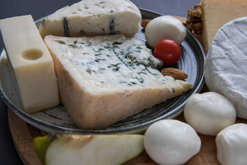 Cheese board close up .  Mixed cheese  .  Parmesan , camembert , brie , mozzarella  and masdam on a gray background top view . 