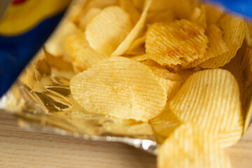 crispy potato chips in snack bag on wood table