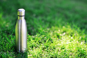 Water bottle. Reusable steel thermo water bottle on green grass. Steel thermo water bottle of...