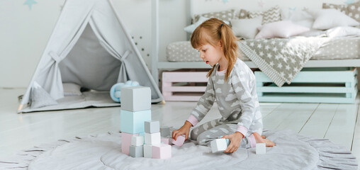 Beautiful little girl playing with wooden toy blocks