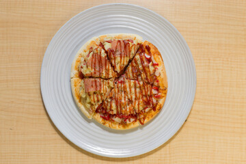 Italian pizza in white plate on wooden table