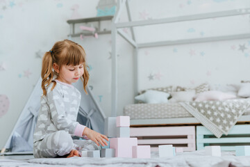 Beautiful little girl playing with wooden toy blocks