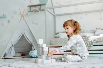 Beautiful little girl playing with wooden toy blocks