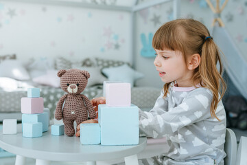 Beautiful little girl playing with wooden toy blocks