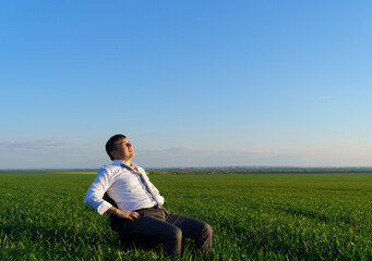 businessman sits in an office chair in a field and rests, freelance and business concept, green grass and blue sky as background