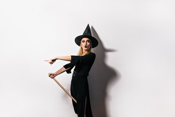 Shocked woman with black lips posing at carnival. Emotional girl in witch costume celebrating...