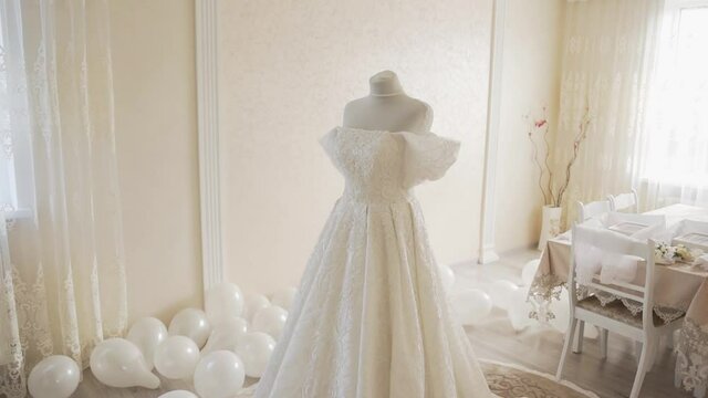 Luxurious lush wedding dress on a mannequin in the room. Clothes for bride. Expensive wedding dress made of beautiful fabric. Wedding dress with ruffled sleeves and sewn lace on the corset and skirt