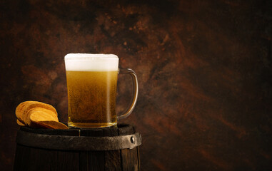 Chips on an old oak barrel with a glass of beer, iron rings, dark background.