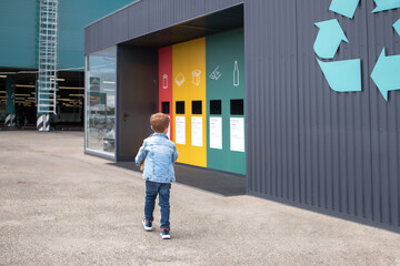 preschooler carries household sorted garbage for recycling into containers. garbage recycling concept.