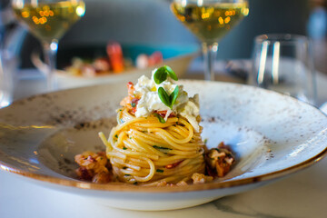 haute cuisine dish with spaghetti with lobster, buffalo stracciatella and a fine white wine. In a luxurious Italian restaurant - 450551062