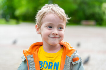Close-up of a cute, happy little boy walking in the park. A happy, joyful child on a walk. The...