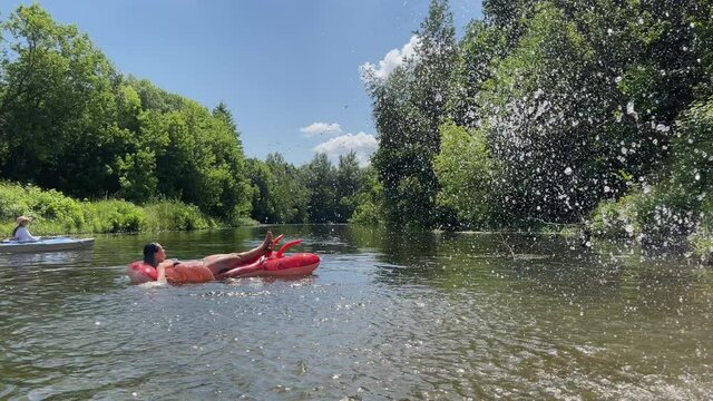 4k Girl on inflatable lobster in river. Summer water activities,