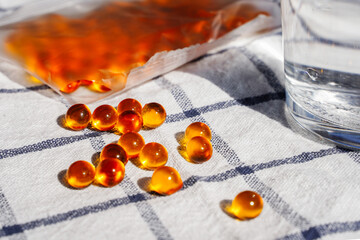 Fish oil capsules and glass of water on the table. Cod liver oil, omega-3. Nutritional supplements. Sport, diet concept.