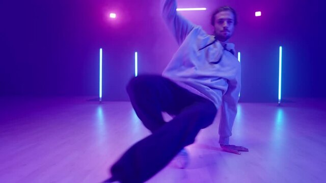 Young man performer in neon lights studio showing hip hop dance in slow mov 4K