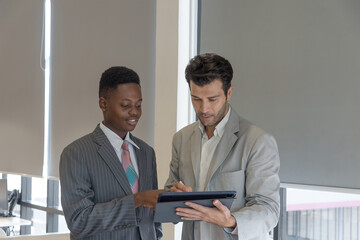Boss teaching African subordinates with care by tablet