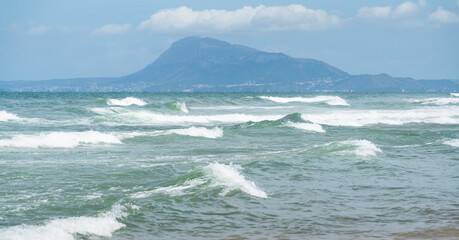 Rolling high ocean waves with view to the mountain of Denia, taken from Daimus, Spain