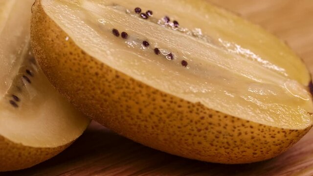 Close-up of a spinning kiwi. Kiwi cut into slices in half rotates on a wooden surfac