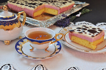 Exquisite Cup of tea and piece of berry cake on a plate, golden and silver dish. Tea time.