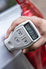 person using film coating thickness gauge device to check car paint. auto coating quality control.