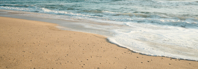 Sandy coastline with white turquoise Sea morning waves.Close up waves on the beach.Texture and Pattern wallpaper backgrounds.