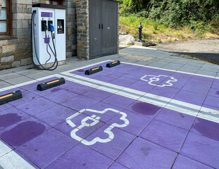 petrol station with a charging point for electric cars with a purple painted floor with a symbol of...