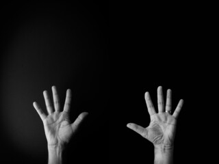 Black and white image of hand demonstrating sign language number ten against black background with empty copy space