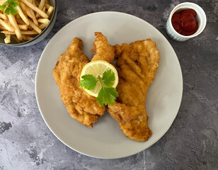 Austrian chicken schnitzel with french fries, ketchup and lemon.