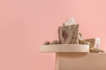 Pieces of halva on modern beige circle and square podium for product on pastel background. Traditional dessert on cube pedestal. Horizontal orientation, side view, copy space.