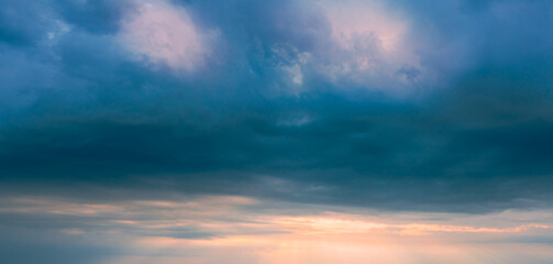 Naklejka na ściany i meble Panorama of stormy sky before sunset. Dark clouds in the sunset sky.