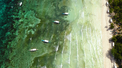 Sandy beach and azure water surrounded by a coral reef. Panglao island, Bohol, Philippines. Summer and travel vacation concept.