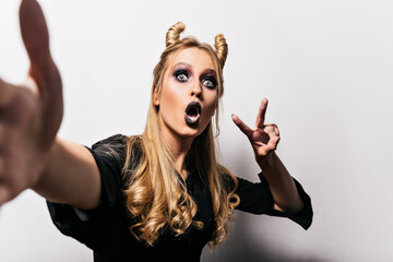 Inspired caucasian woman in witch outfit making selfie. Amazing girl with dark makeup preparing for...