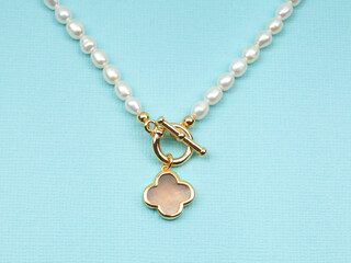 Fototapeta na wymiar Luxury elegant baroque pearl necklace with pendant on bright turquoise textured background